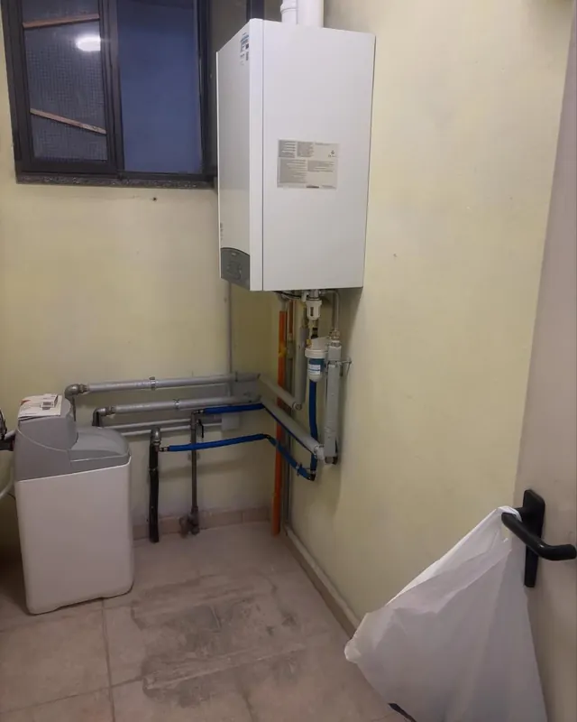Caldaia murale installata con addolcitore e tubazioni a vista